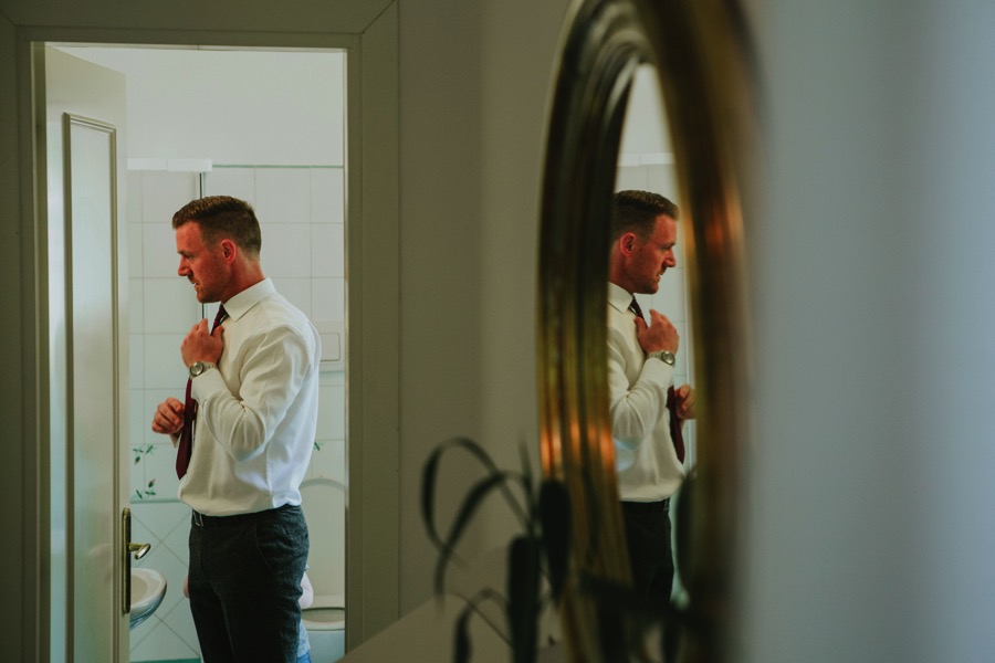 best man getting ready while reflecting in the mirror