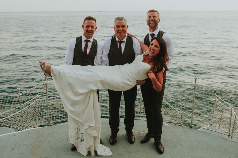 best men and groom holding the bride for a group picture