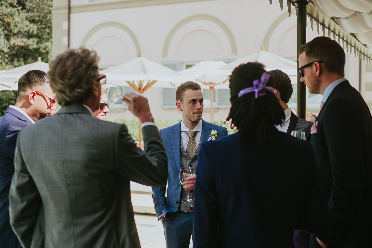 groom wearing a blue suit having a drink before wedding