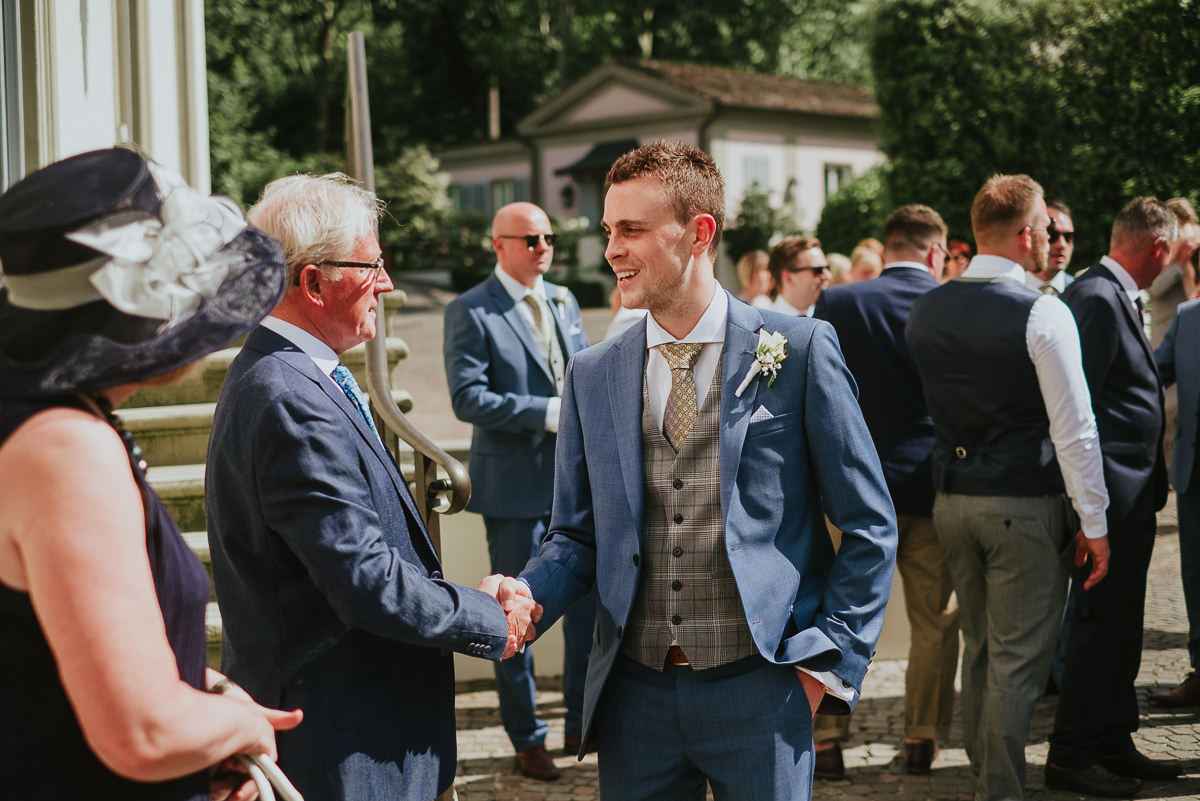 groom wearing a blue suit shaking hands before his wedding