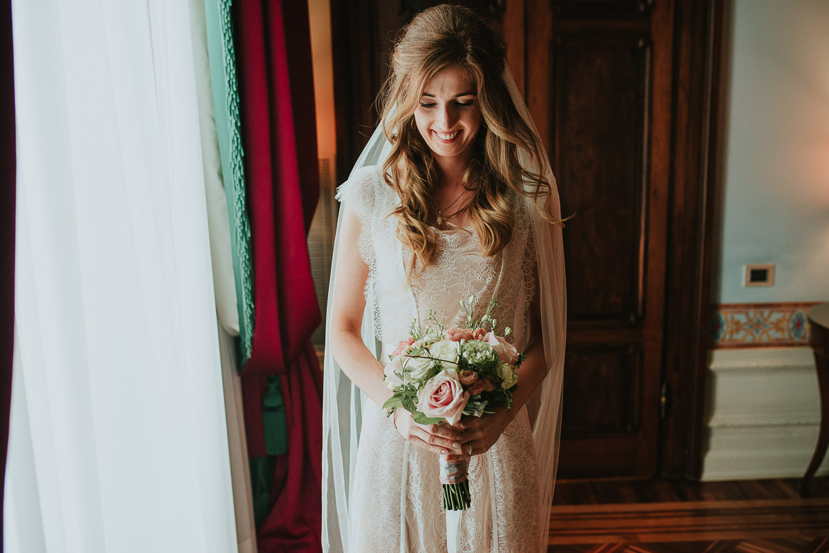 natural bride portrait with window light looking at the flower bouquet