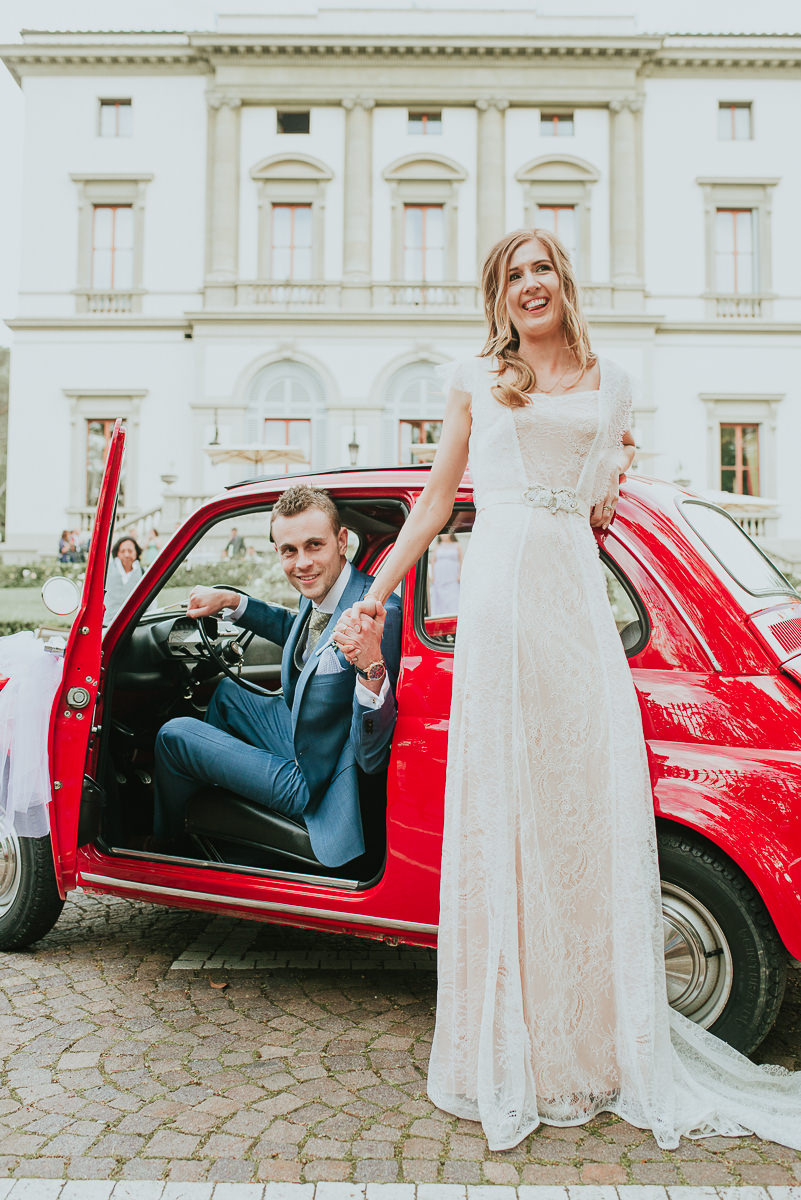 bride and groom in a typical red italian 500 cinquecento dressed up for wedding