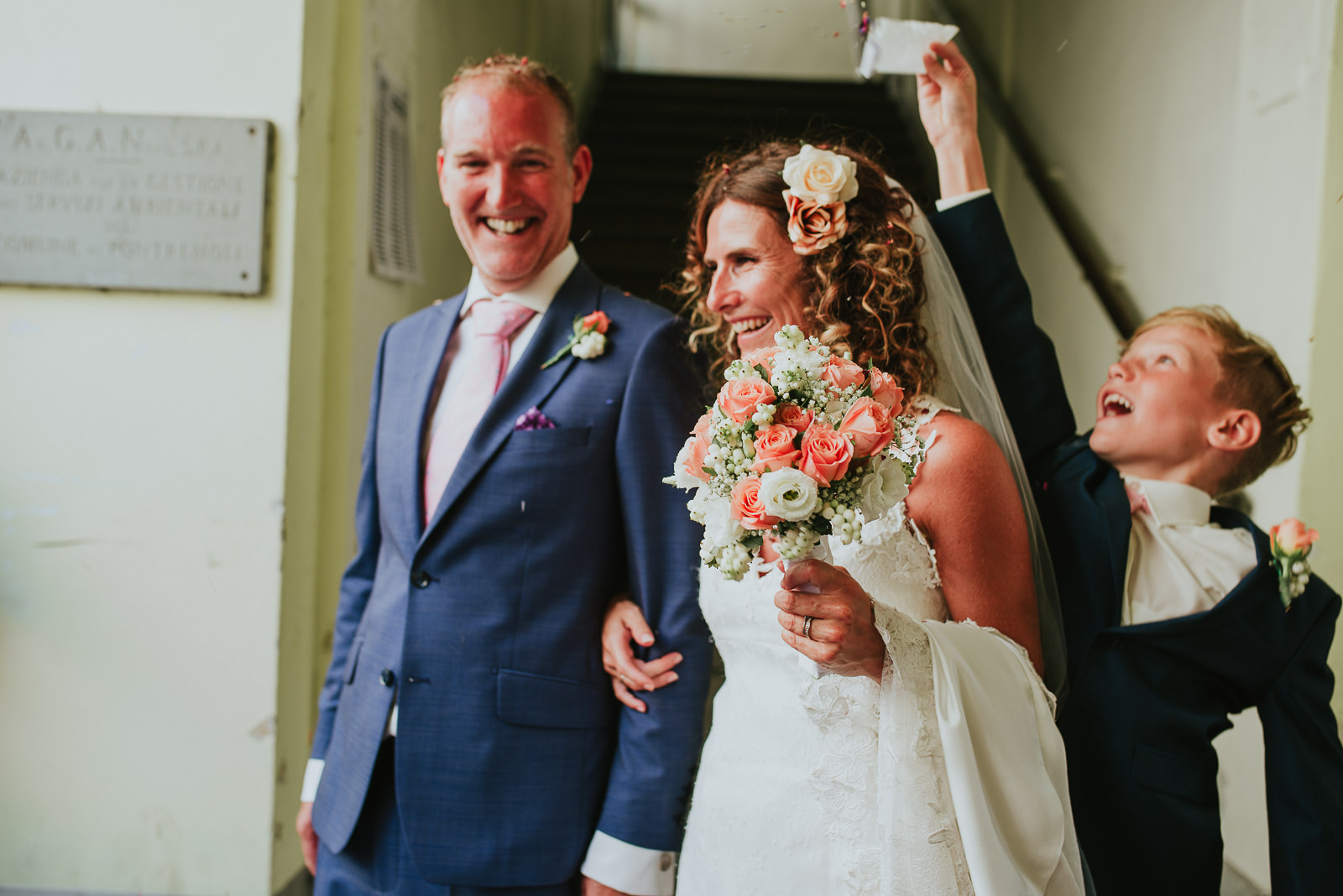 ring bearer boy throws confetti to bride and groom